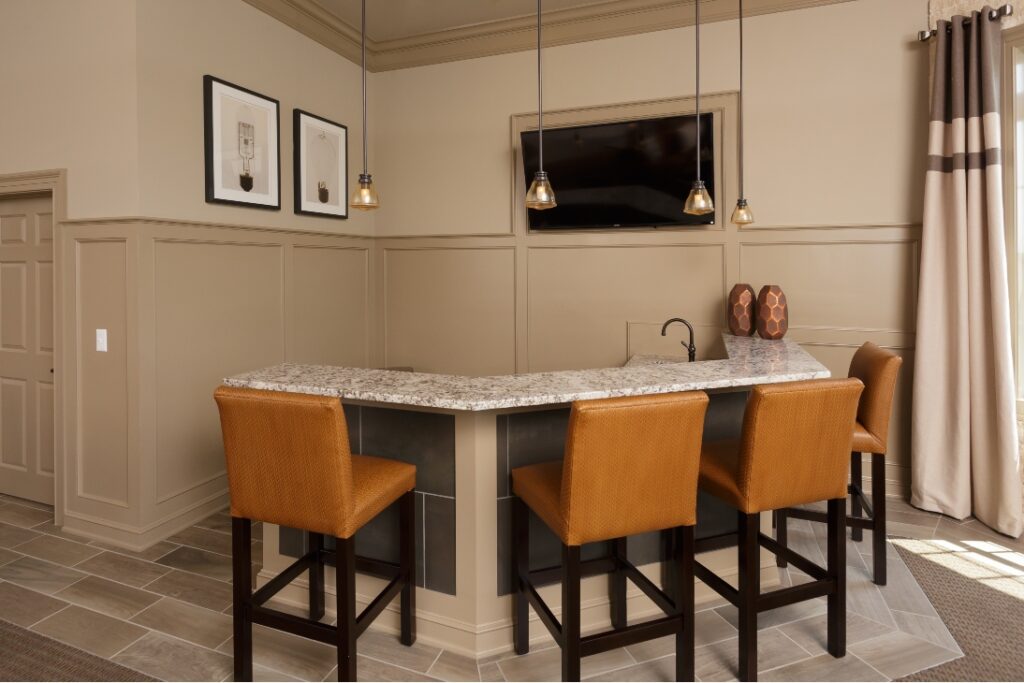 A High-Top Marble Bar Complete With Chairs And Custom Trim Done By Commercial Contractors From Foggy Ridge Interiors