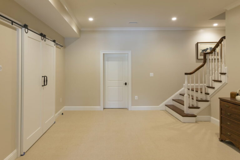 Full View Of A Remodeled Basement Bedroom With Wall-To-Wall Carpeting, Barn Style Door Closet, And Recessed Lighting.