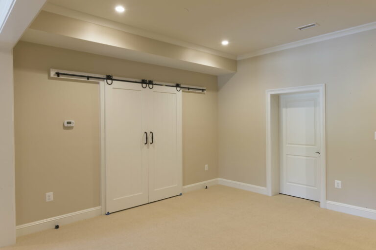 A Remodeled Basement Bedroom Replete With Wall-To-Wall Carpeting, Barn Style Door Closet, And Recessed Lighting Finished By Our Team Of Experienced Basement Remodelers In Lancaster, Pa.