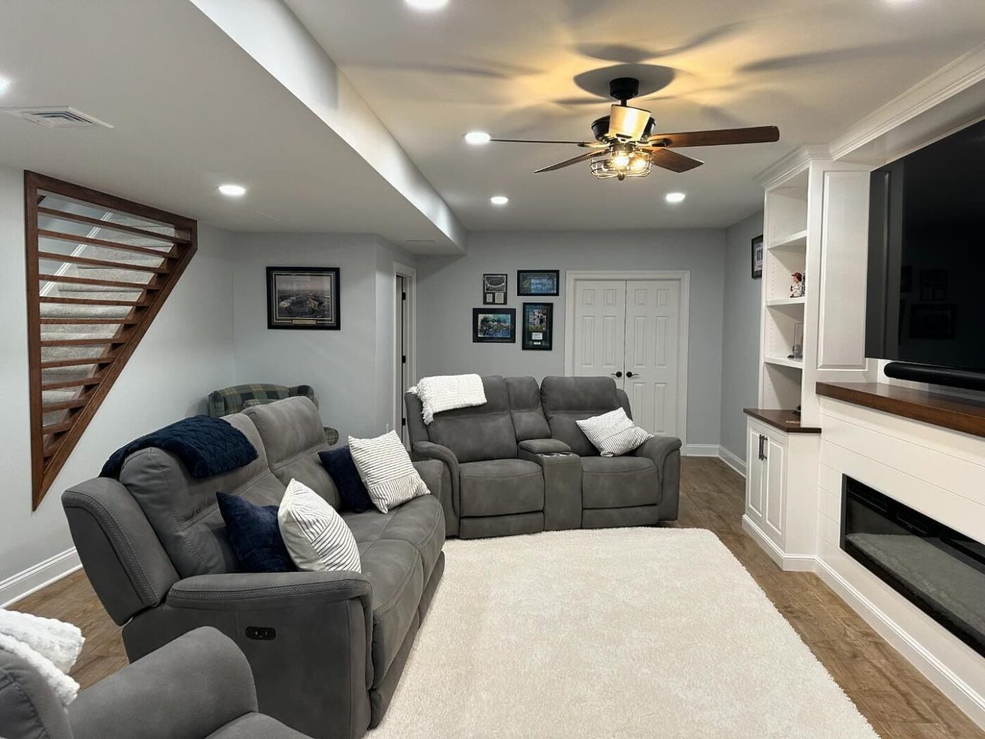 A Newly Finished Basement With Comfy Couches, Brand New Lighting, Walls, And A Stripe Design On The Staircase Wall, With An Area For Games In The Back, Such As Table Tennis And Foosball, In Lititz Pa