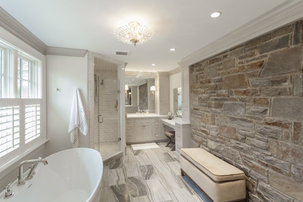 A Newly Remodeled Bathroom With A Stone Brick Wall, A Classic Looking Bath Tub, And A Seat In Darby Pa