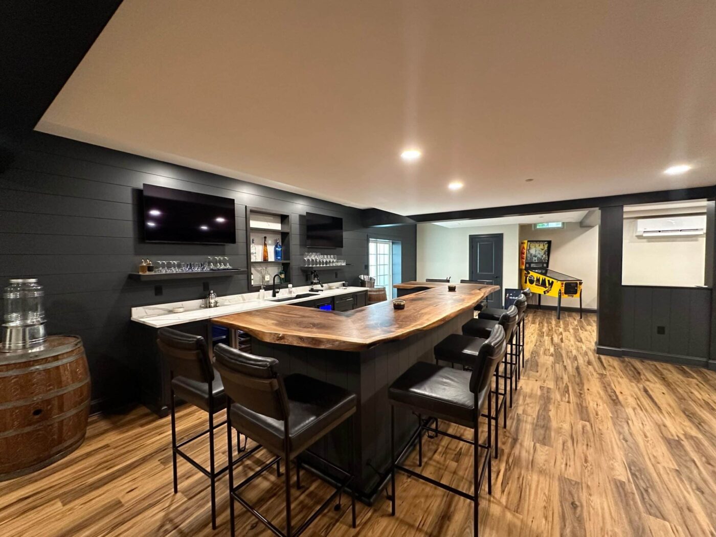 A Newly Renovated Basement With Fancy Bar Seating, Two Tvs On A Black Wall In Newtown Square Pa